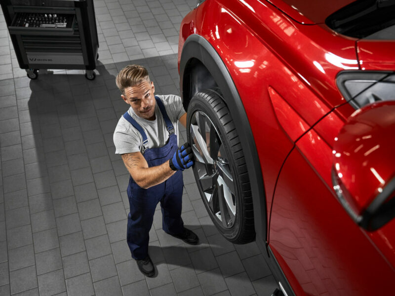 mężczyzna wymienia opony w czerwonym volkswagenie