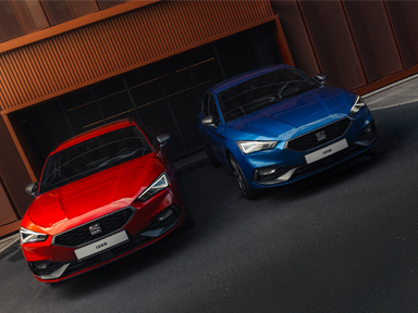 czerwony i niebieski seat leon stoją obok siebie